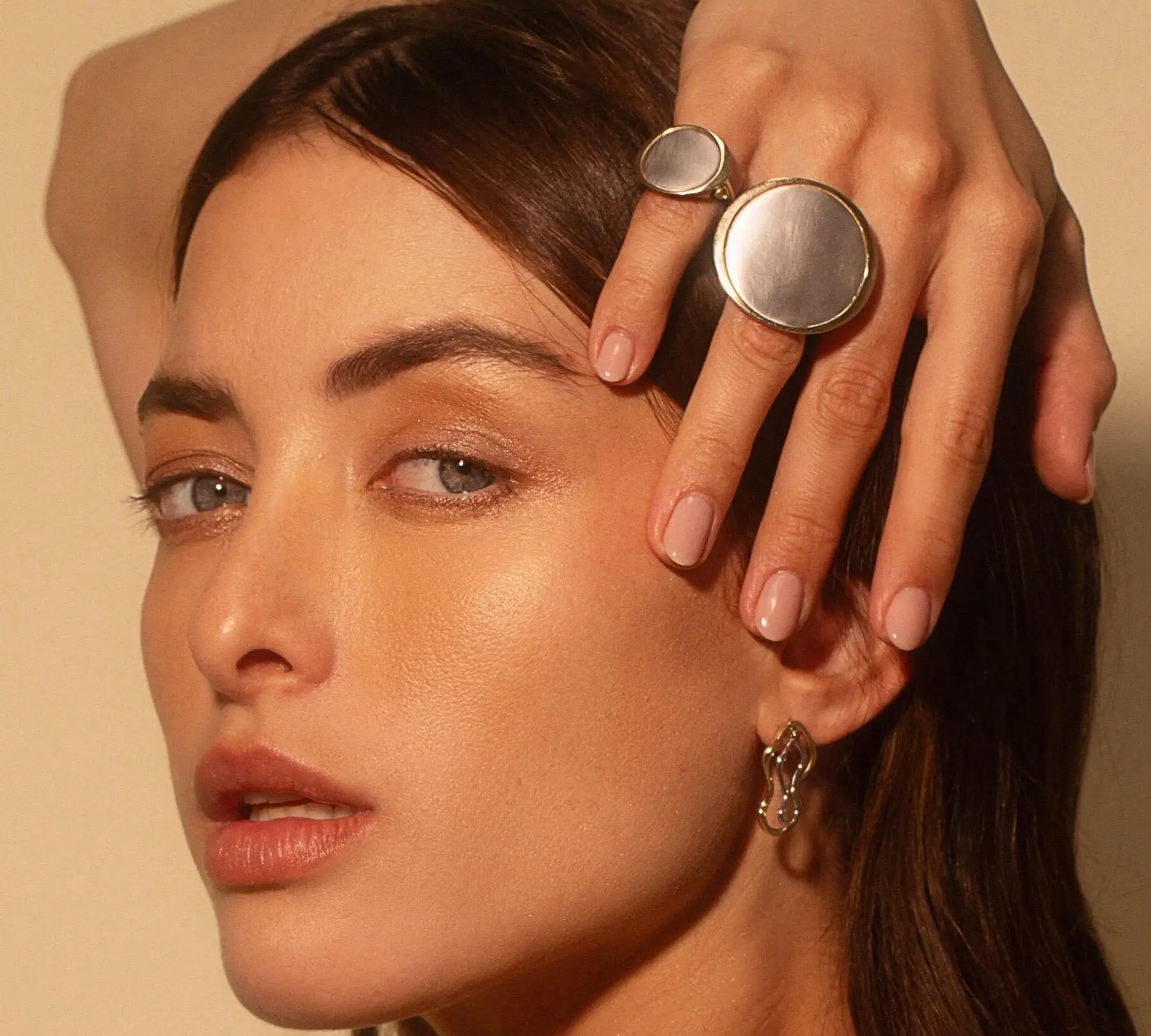 Woman with hand over her head, wearing the Medium Kelly Statement Ring + The Large Kelly Statement Ring