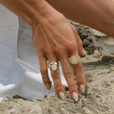 Hand with rings on a sandy surface