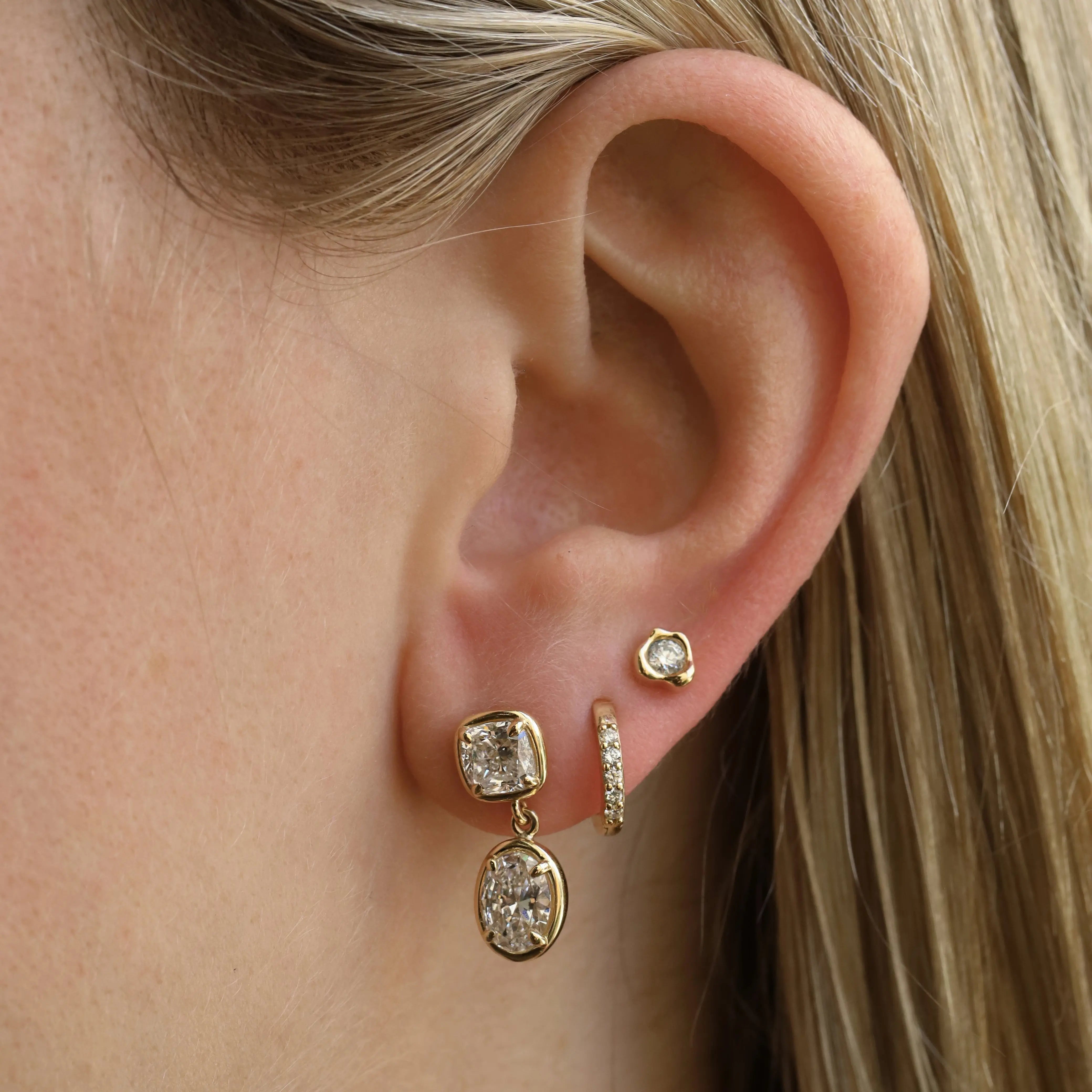Close-up of an ear wearing gold earrings with diamonds.