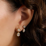 close up of woman's ear with curly hair wearing two drop diamond earrings in yellow gold