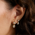 Close up of woman's ear with curly brown hair showing two diamond drop earrings - Large Lisse Dangle Earrings and Lisse Dangle Earrings