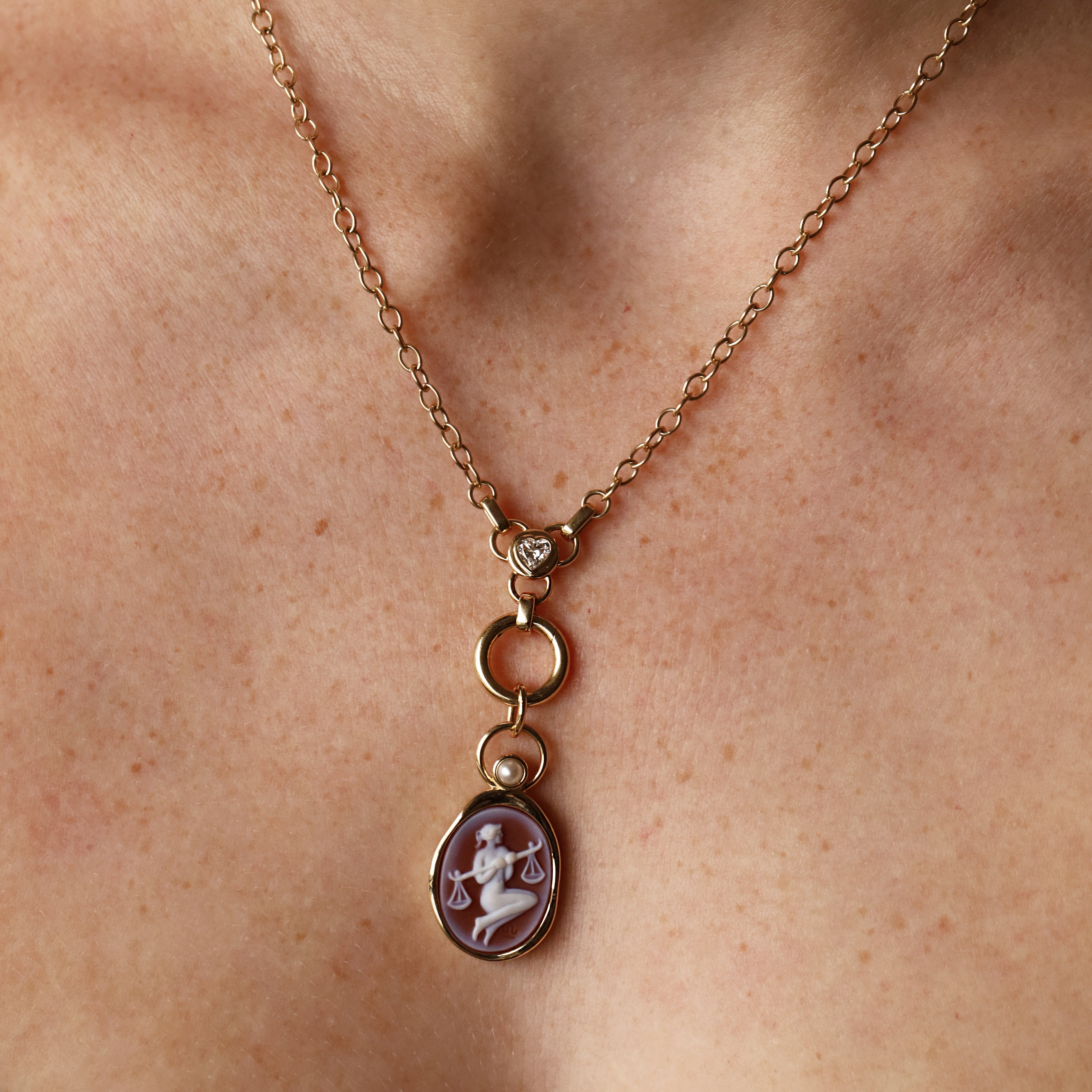 Libra Zodiac Orange Agate Carving with Pearl pendant – Libra holding her scales carved in white on orange agate in 14k yellow gold, with a white pearl floating in an open gold ring