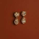 Gold earrings with diamonds on a brown background