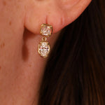 Gold earrings with diamonds worn by a person.