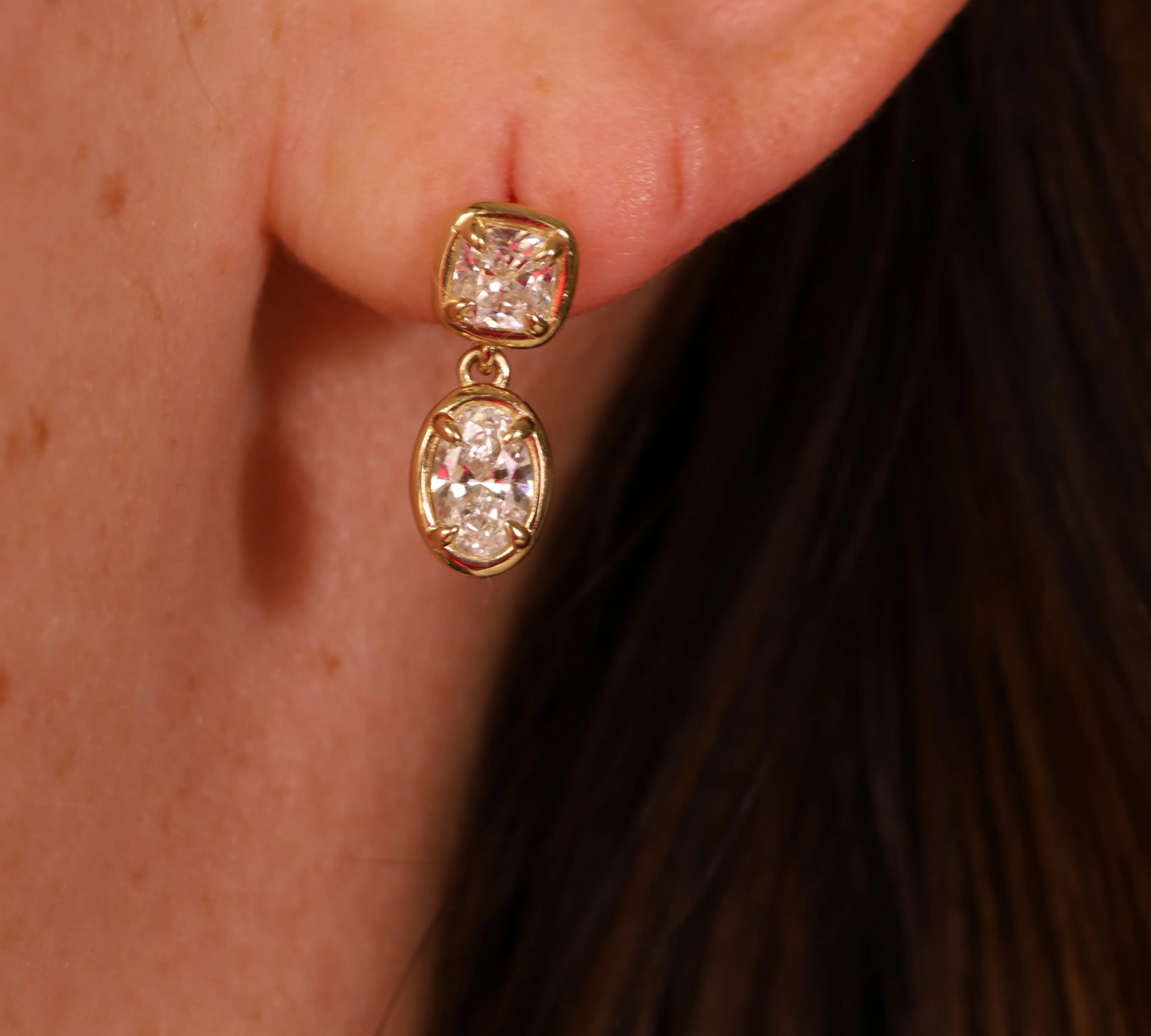 Gold earrings with diamonds worn by a person.