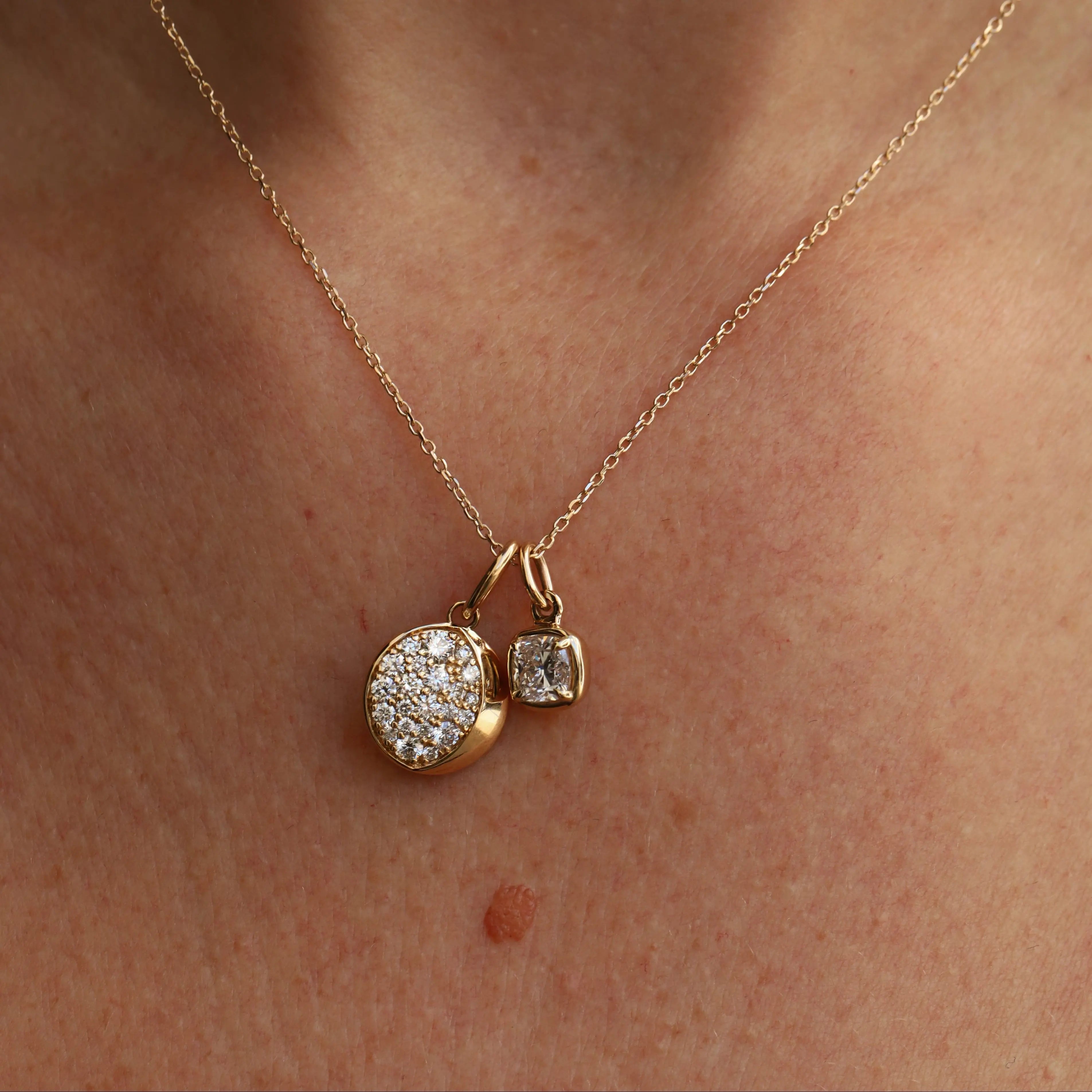 Gold necklace with two pendants on a person's neck
