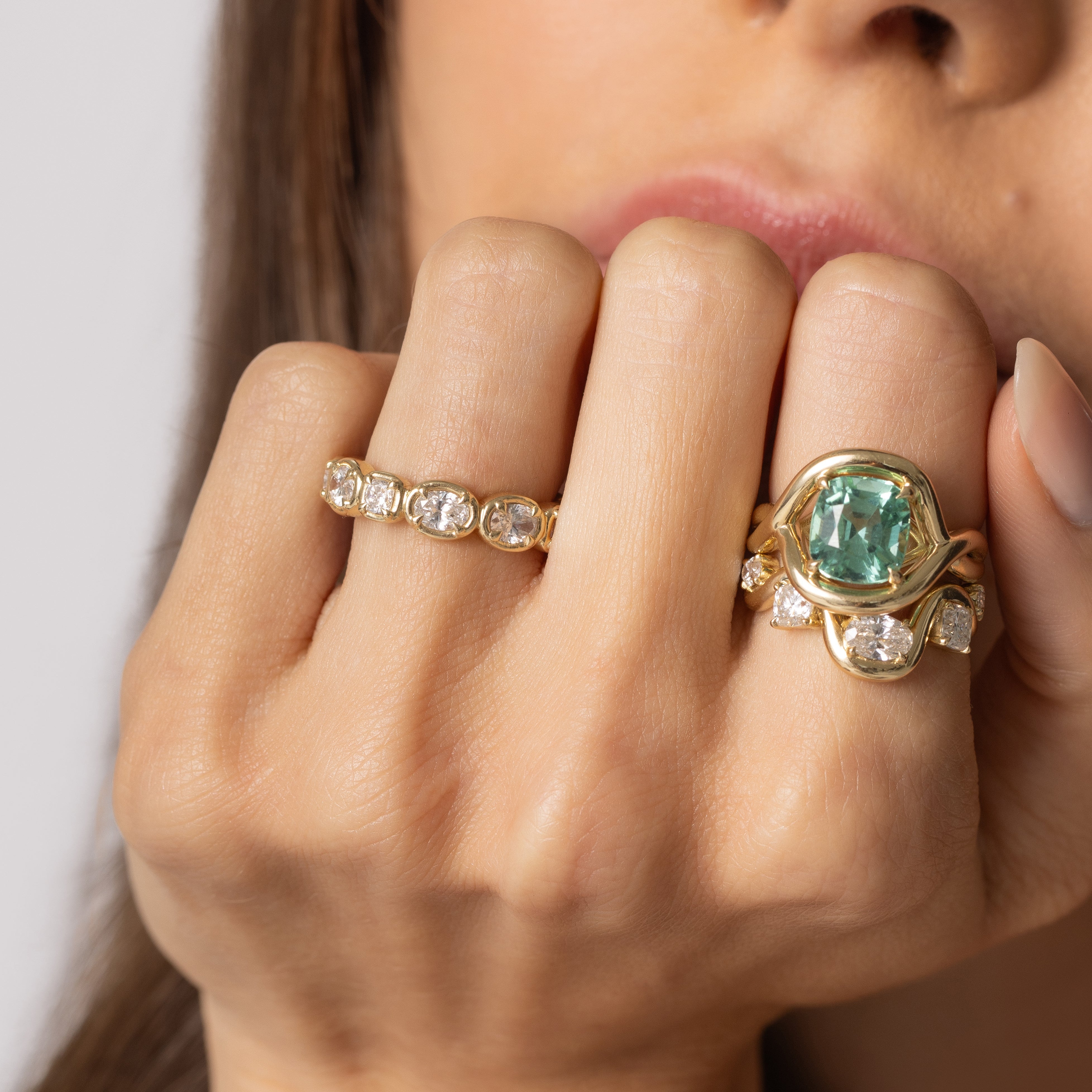 Close up of model with hand resting on her face, featuring multiple Soleil Collection rings