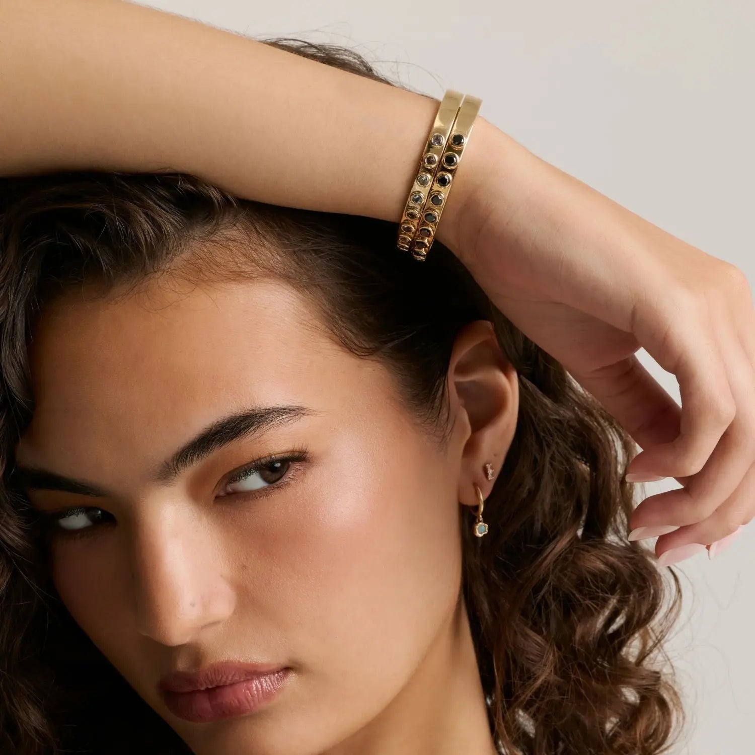 Model with curly hair wearing the Little Black Diamond Cuff on her wrist