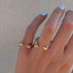 Close up of woman's hand with two horseshoe rings that are yellow gold and have diamonds