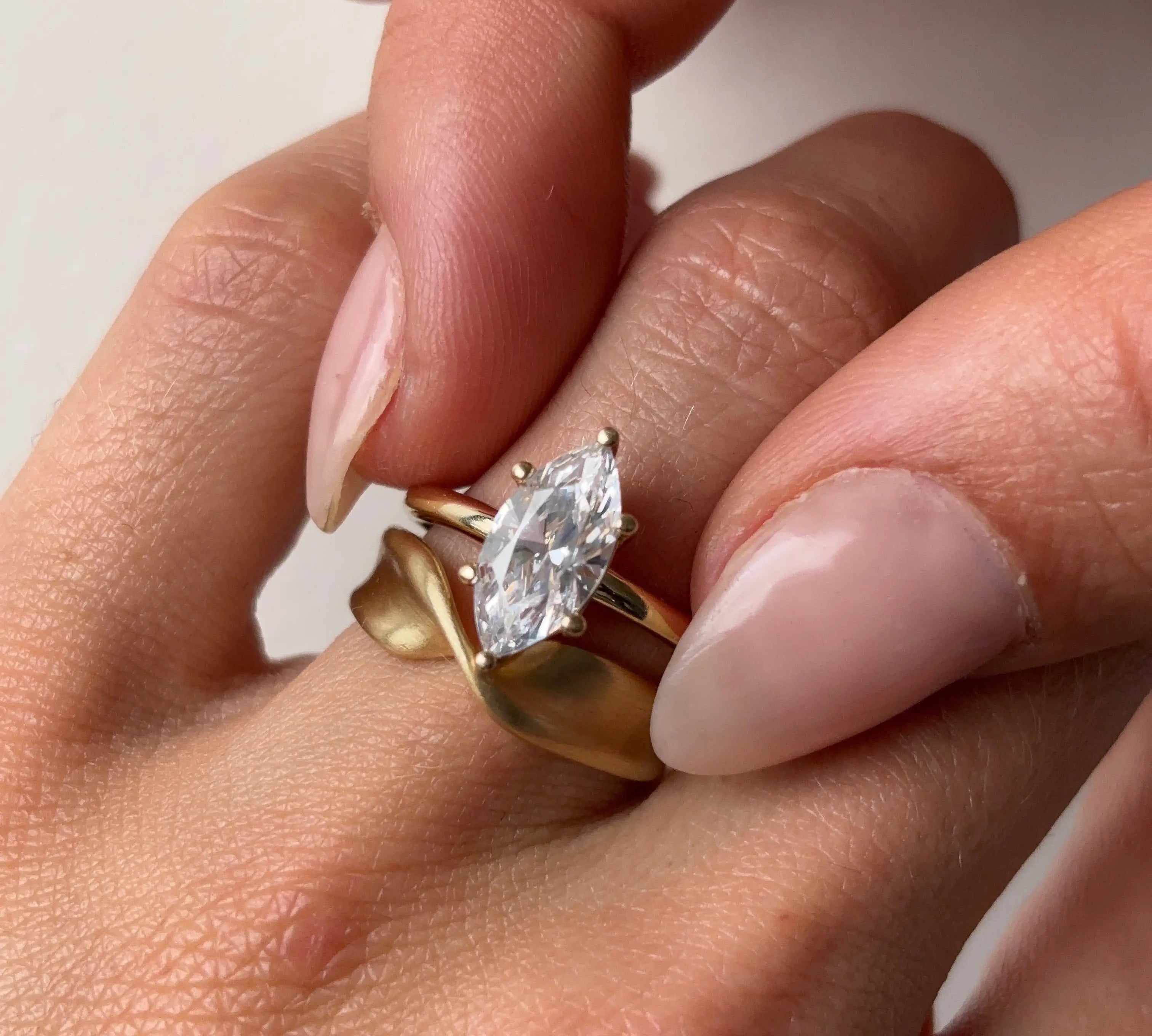marquise diamond ring and gold twist ring on hand