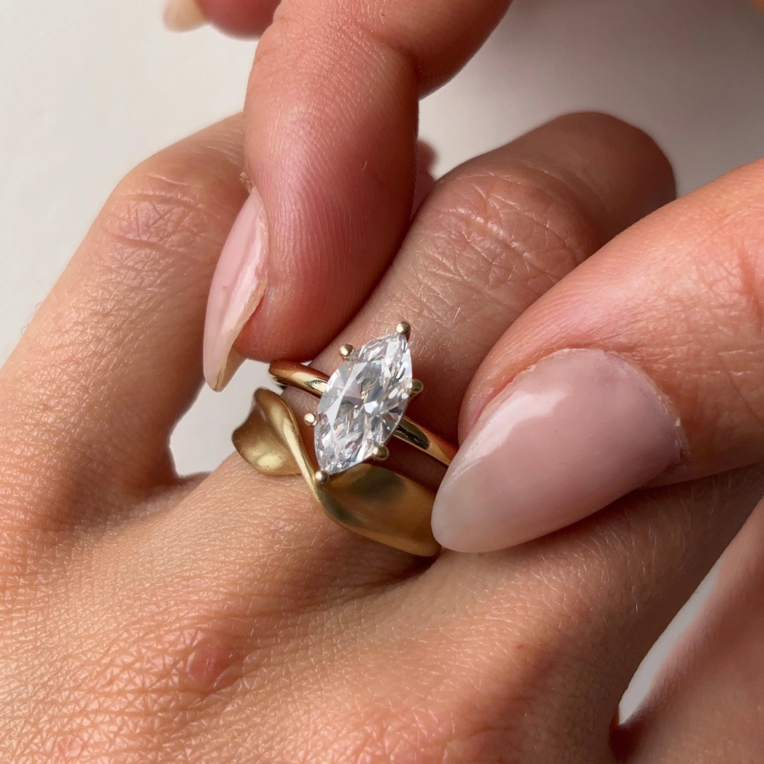 marquise diamond ring and gold twist ring on hand