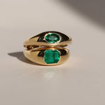 Gold ring with emerald stones on a light background