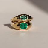Gold ring with emerald stones on a light background