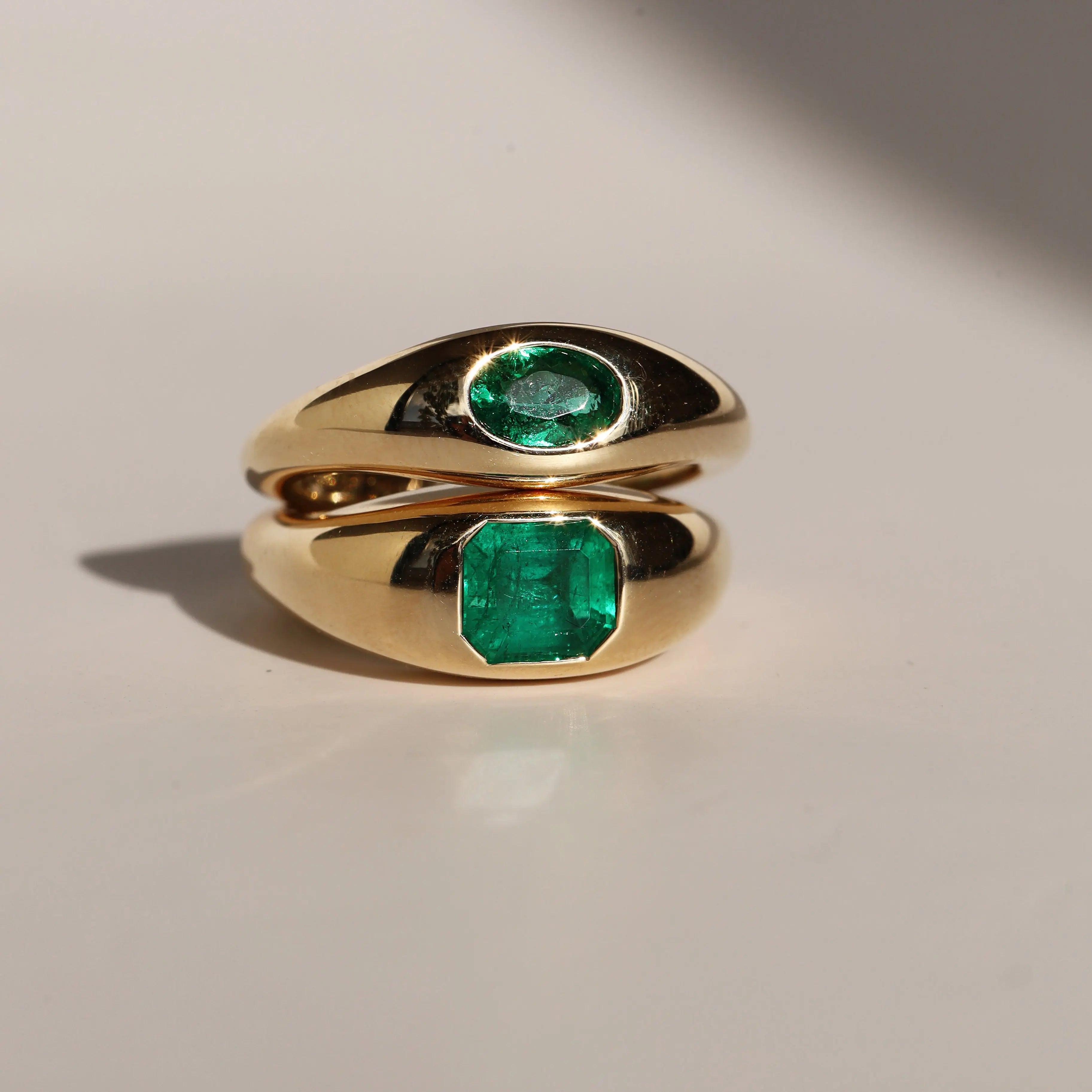 Gold ring with emerald stones on a light background