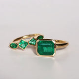 Gold ring with emerald stones on a light gray background