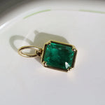 Gold pendant with a green gemstone on a white background