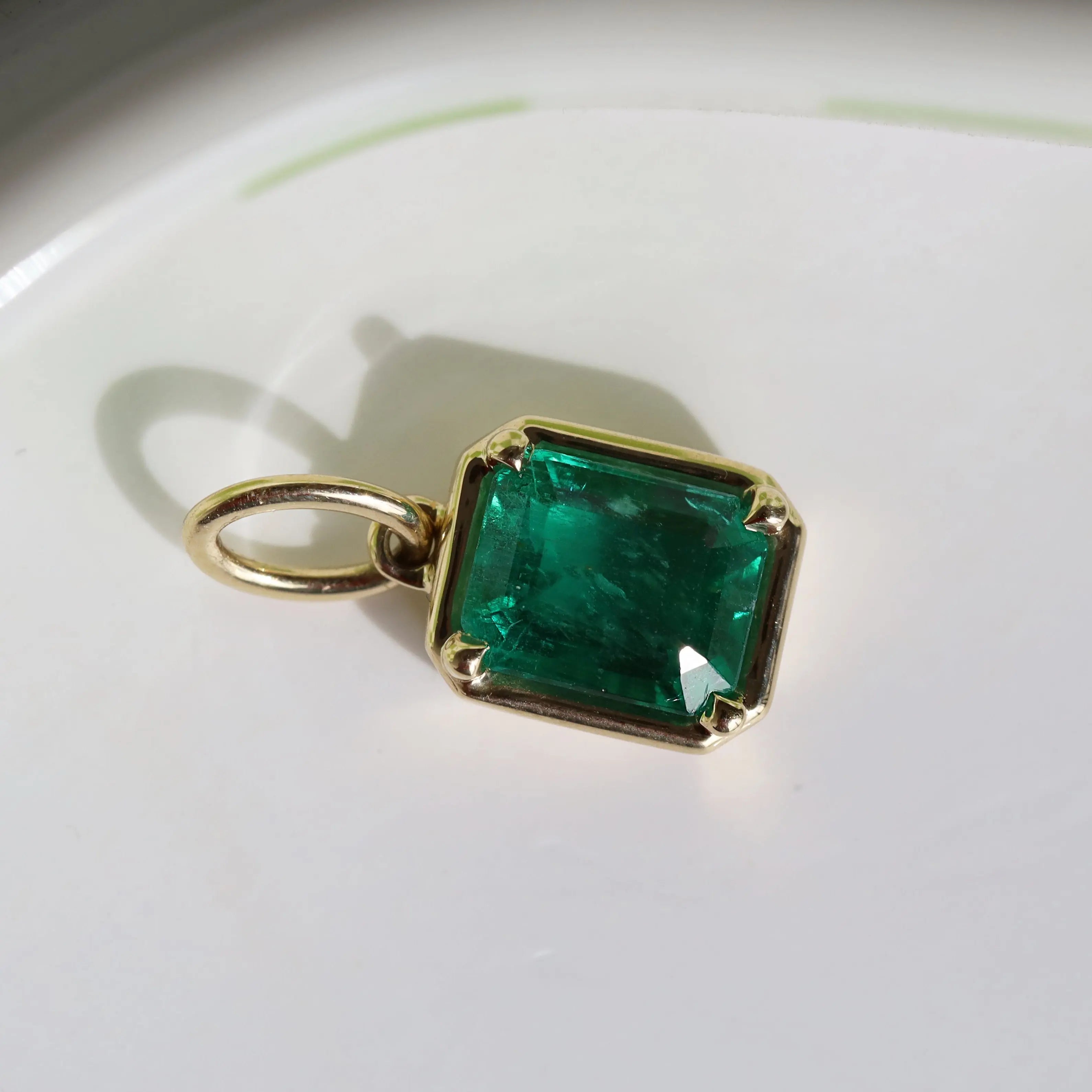 Gold pendant with a green gemstone on a white background