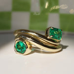 Gold ring with emerald stones on a checkered background