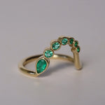 Gold ring with green gemstones on a gray background
