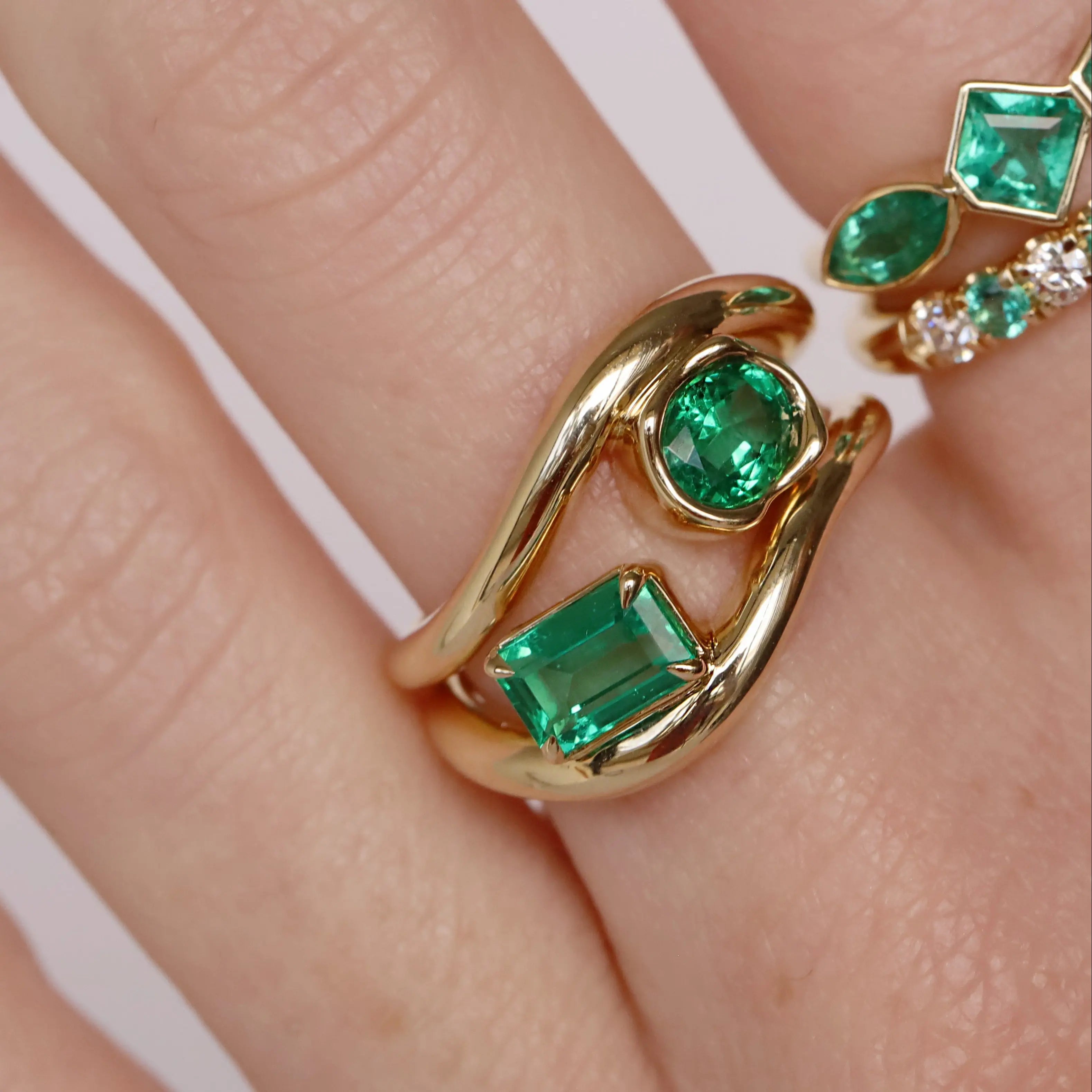 Gold ring with emerald stones on a hand