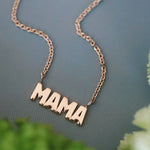 Yellow gold 'MAMA' necklace on a green background