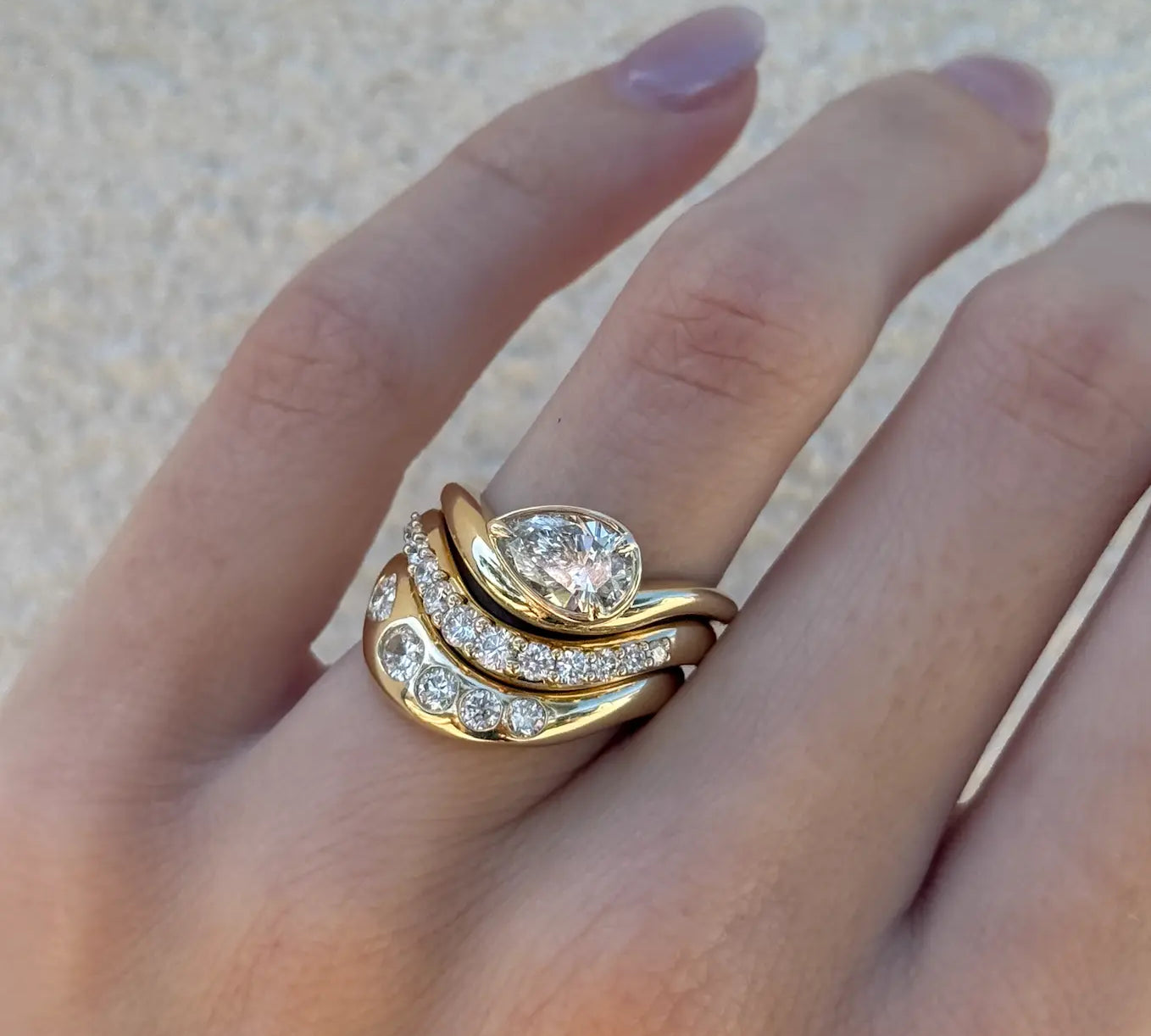 Margot Pear Wave Ring in a stack of yellow gold diamond wave rings on the hand