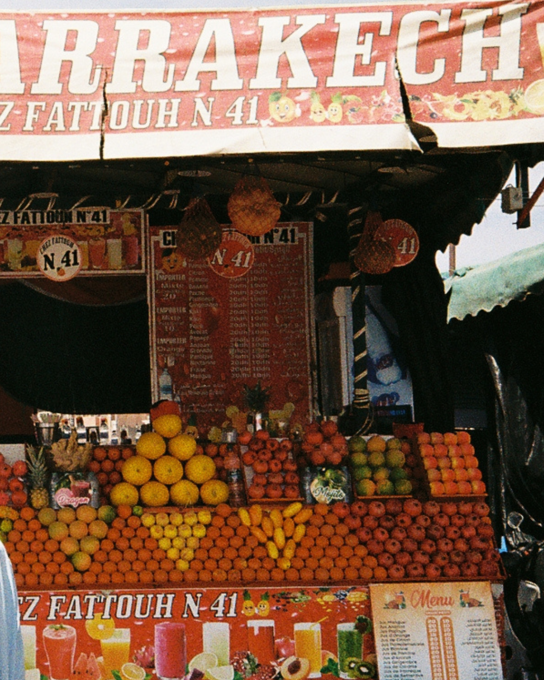 Fresh juice stall no. 41 in a Marrakech market, piled with oranges, grapefruit and bananas under a red sign