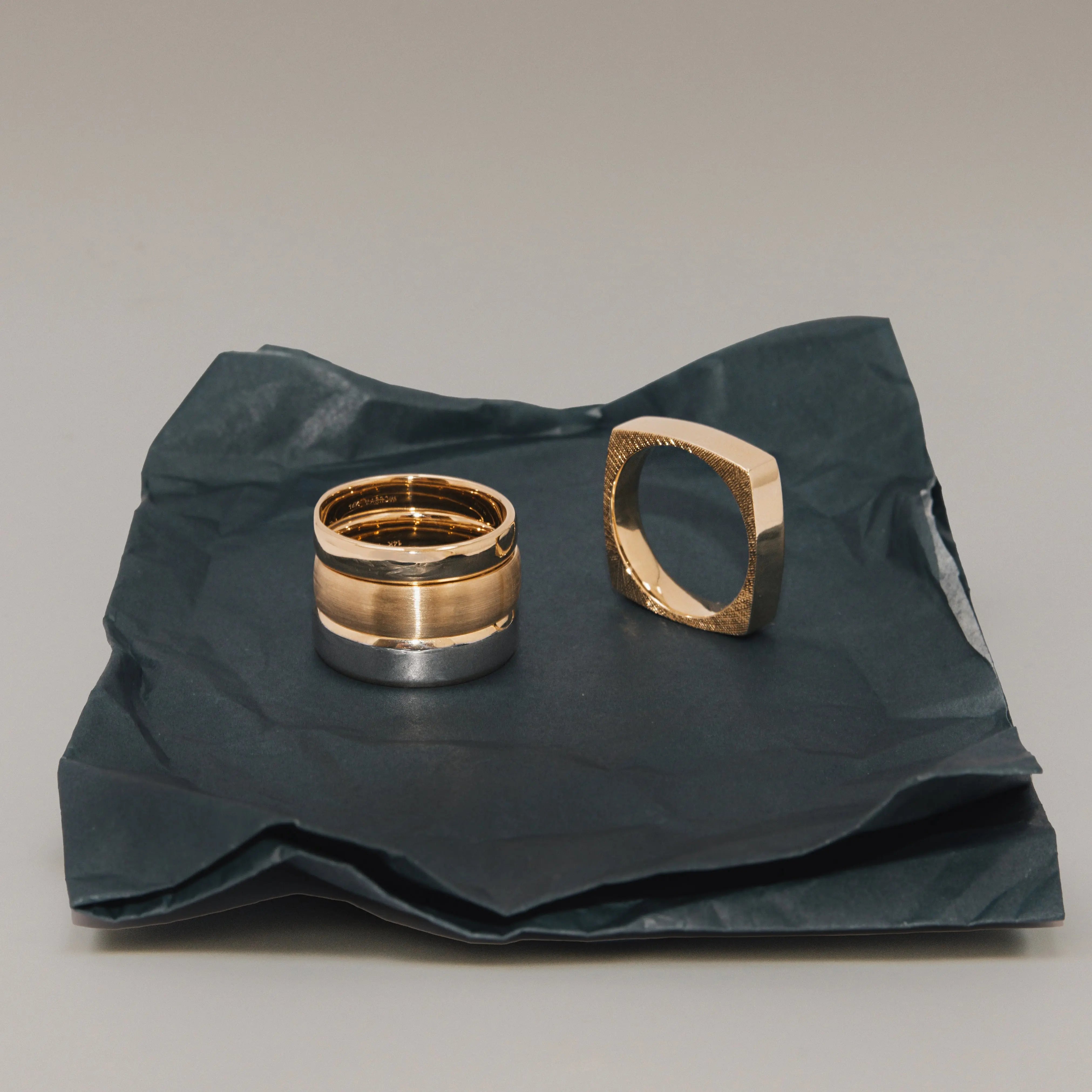 Two gold rings on a crumpled black paper background