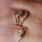 Close up of hand with multiple yellow gold and diamond rings styled together