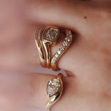 Close up of hand with multiple yellow gold and diamond rings styled together