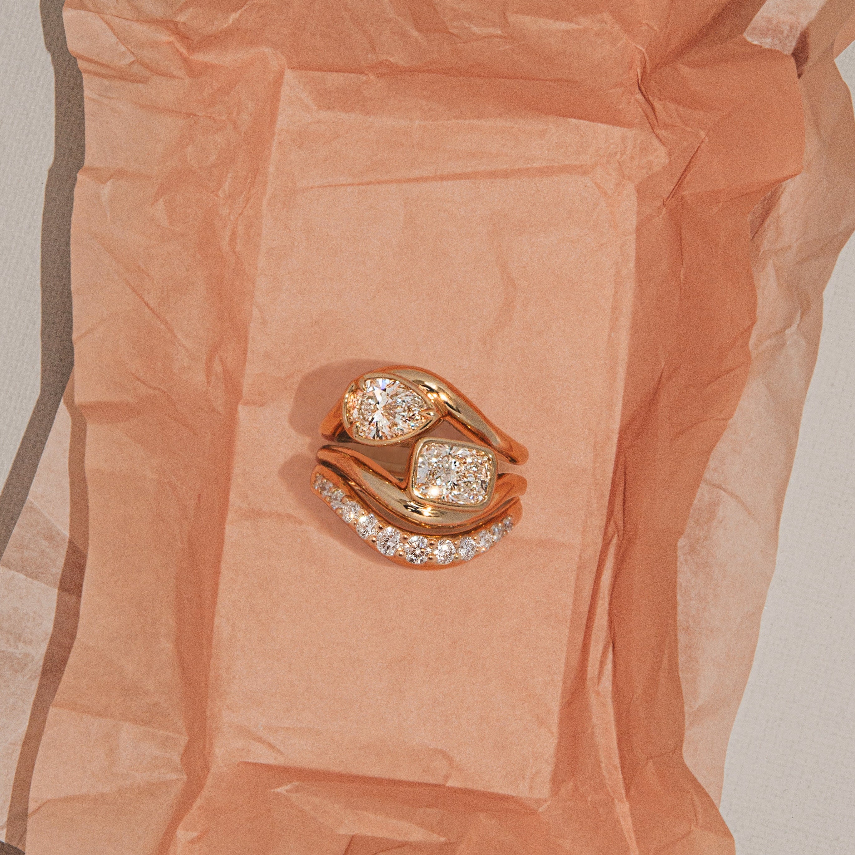 Gold ring with diamonds on a textured peach-colored fabric background