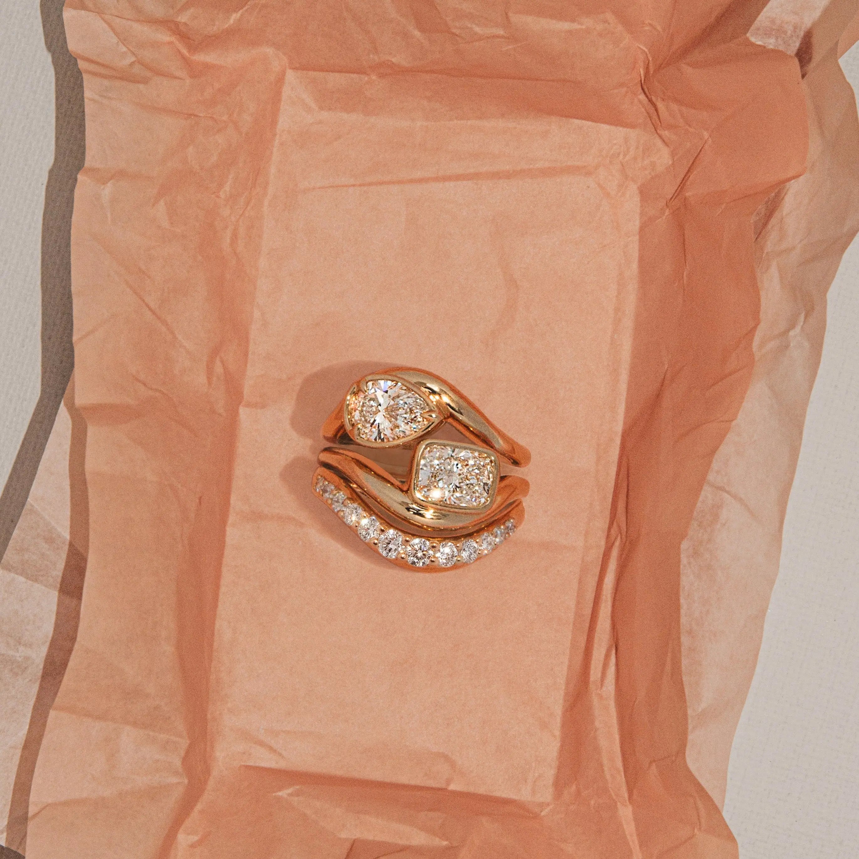 Gold ring with diamonds on a textured peach-colored fabric background