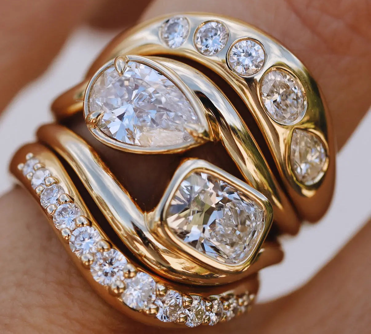 close up of yellow gold and diamond wavy rings stacked together