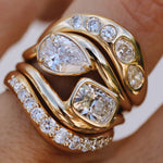 close up of yellow gold and diamond wavy rings stacked together