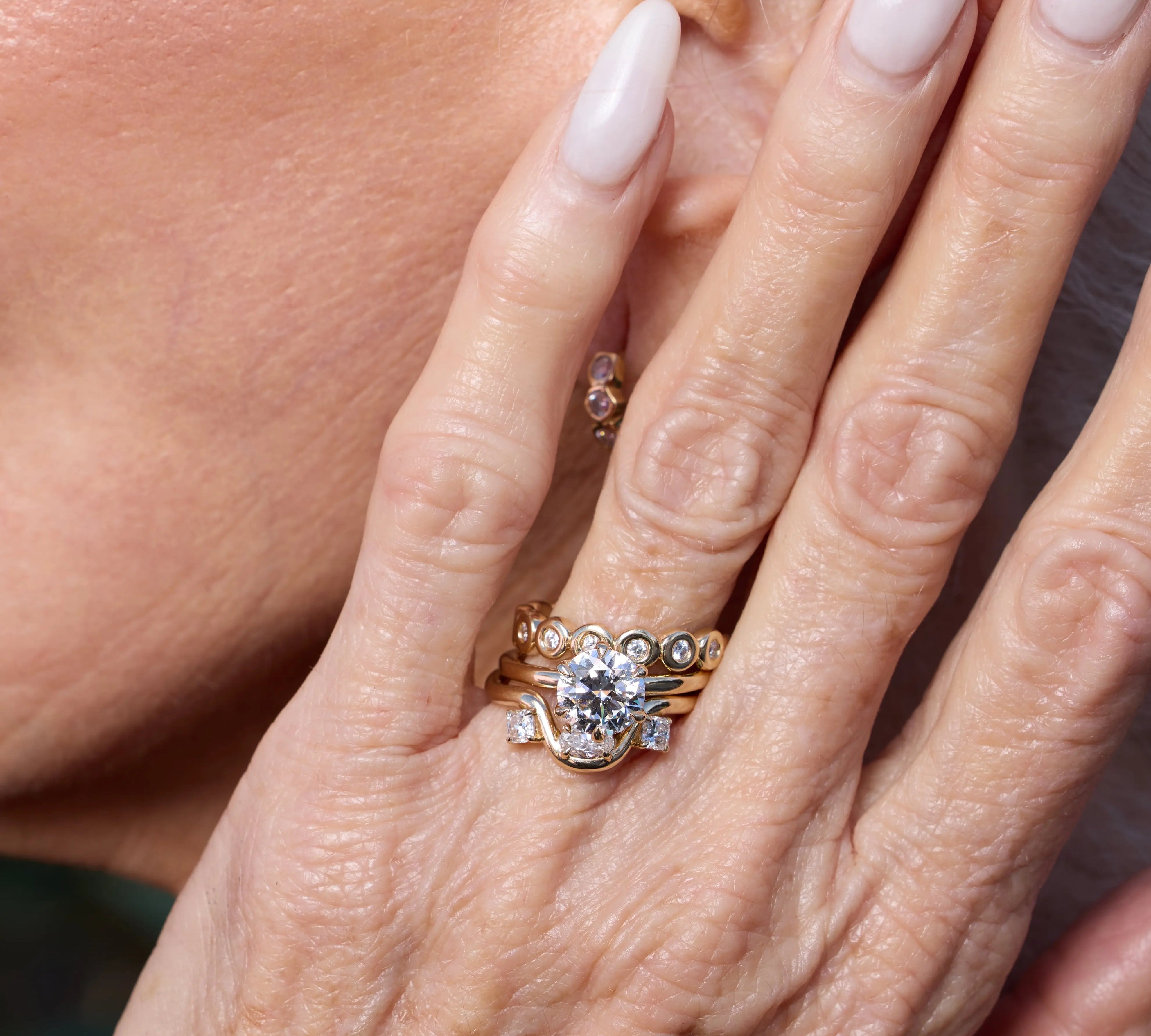 Close-up of a hand wearing a diamond ring with another ring in the background.