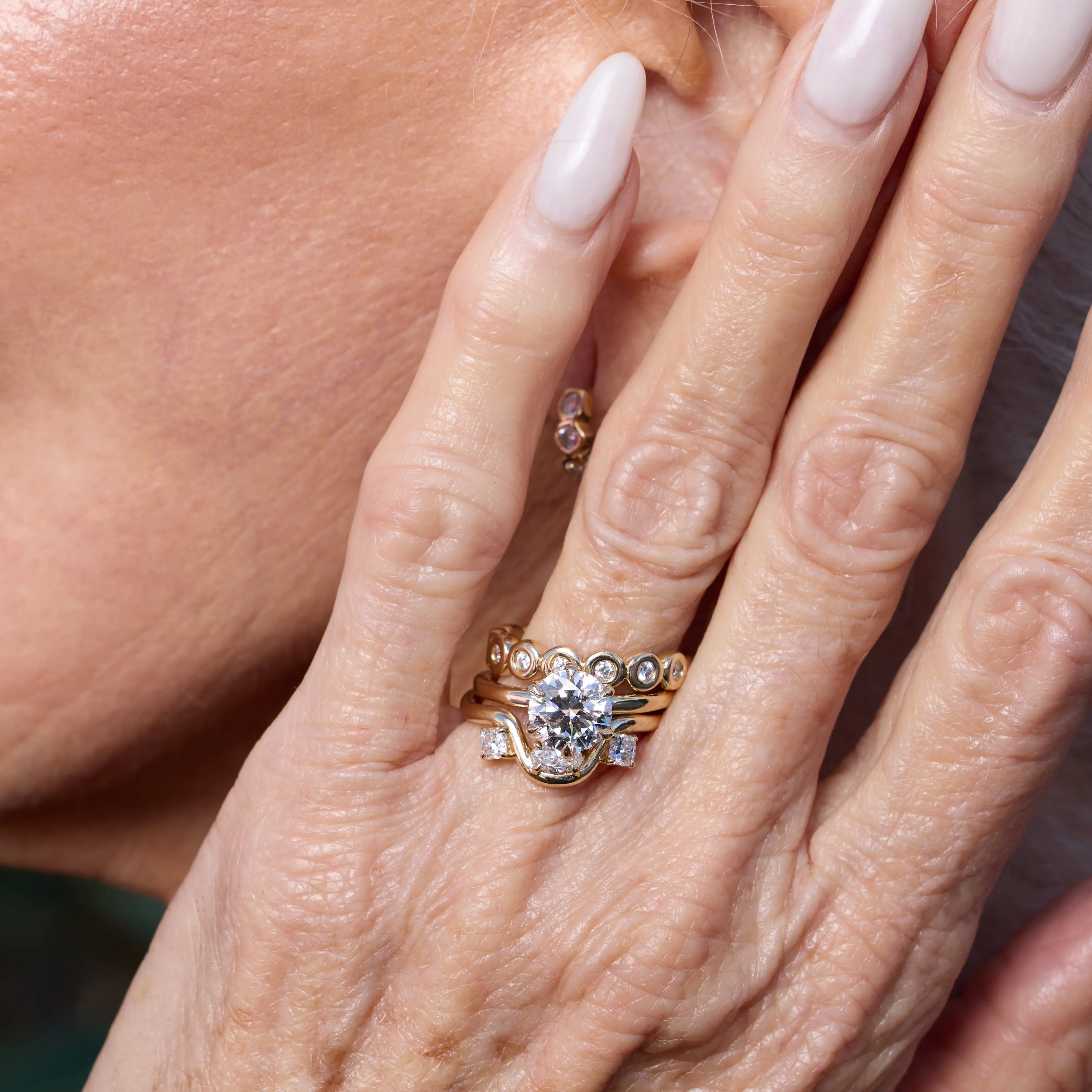 Close-up of a hand wearing a diamond ring with another ring in the background.