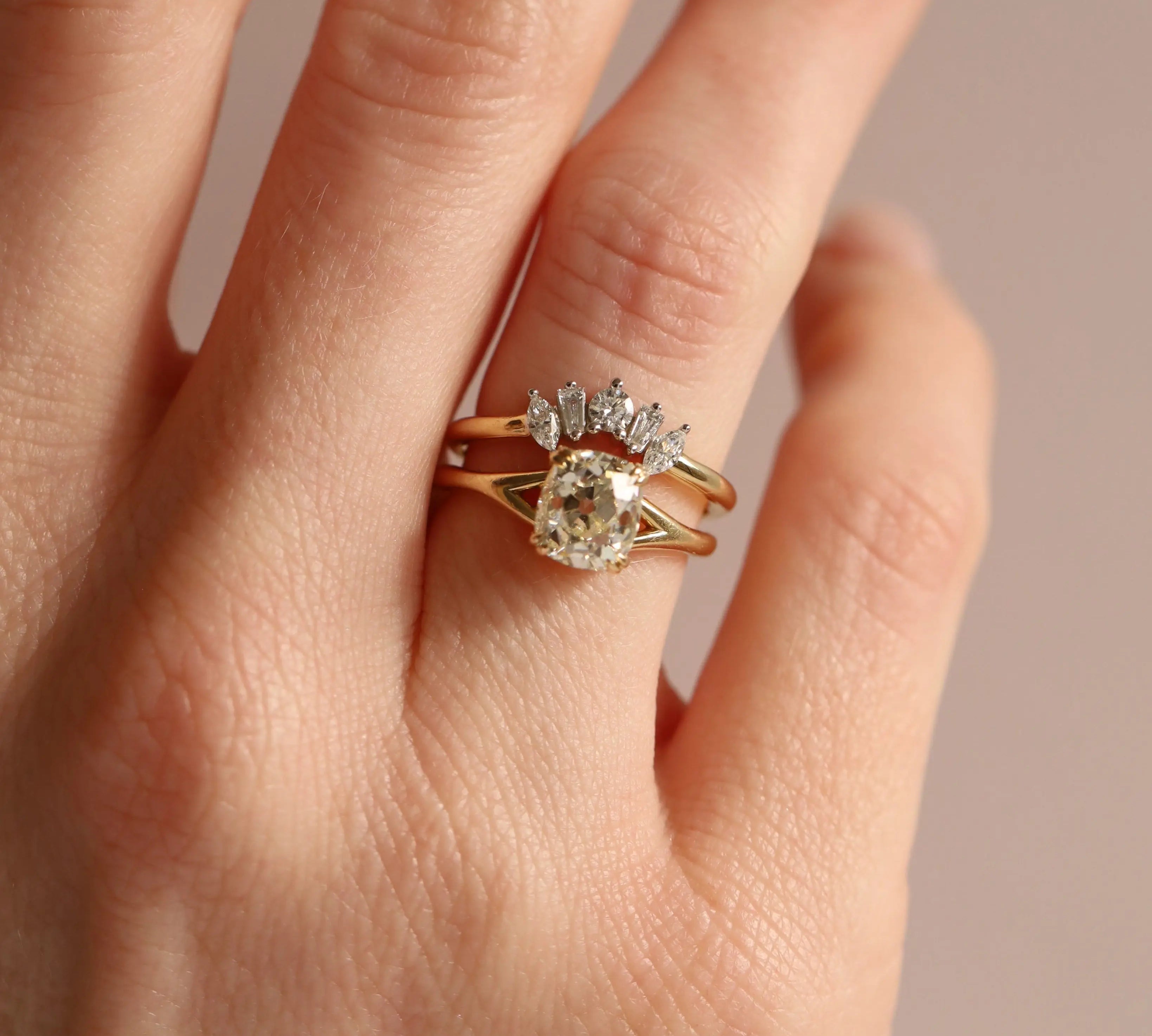 Gold ring with a diamond on a hand against a neutral background
