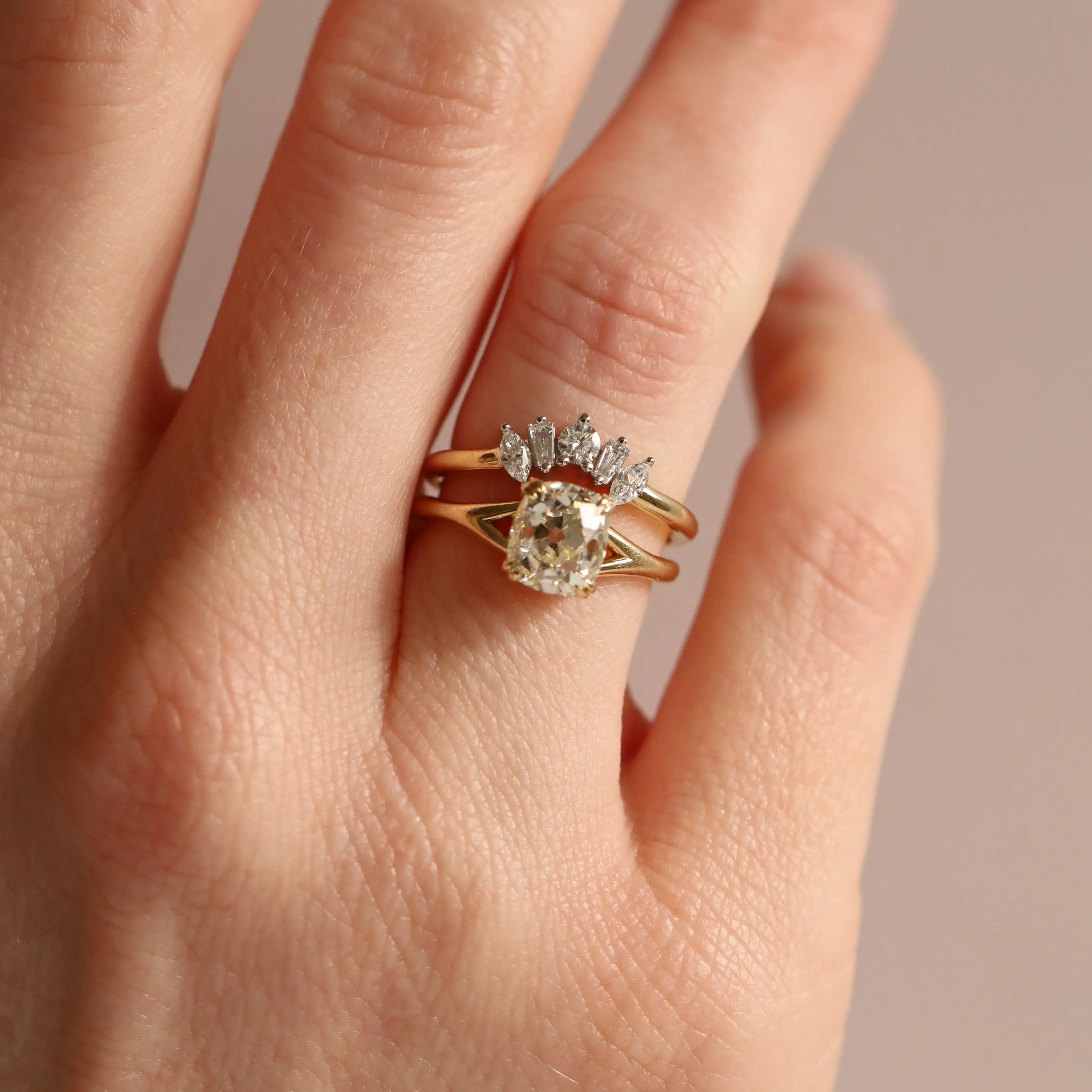 Gold ring with a diamond on a hand against a neutral background