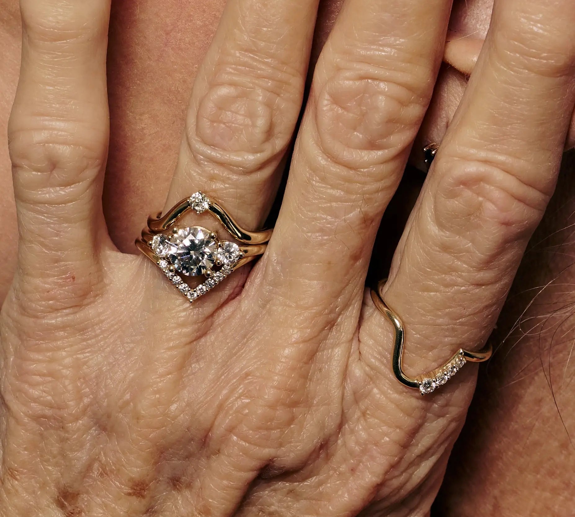 Close-up of a hand wearing a diamond ring with another ring on a different finger.
