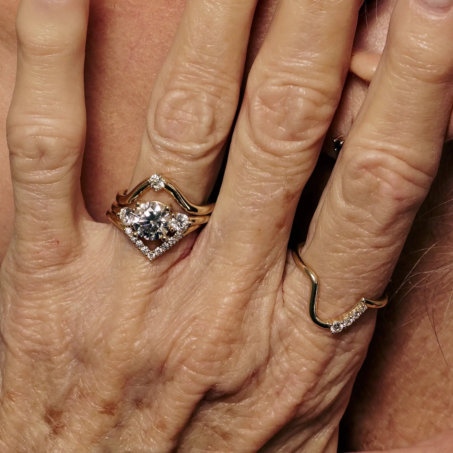 Close-up of a hand wearing a diamond ring with another ring on a different finger.