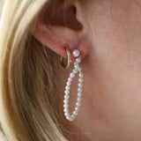 Pearl earring worn by a person with blonde hair.