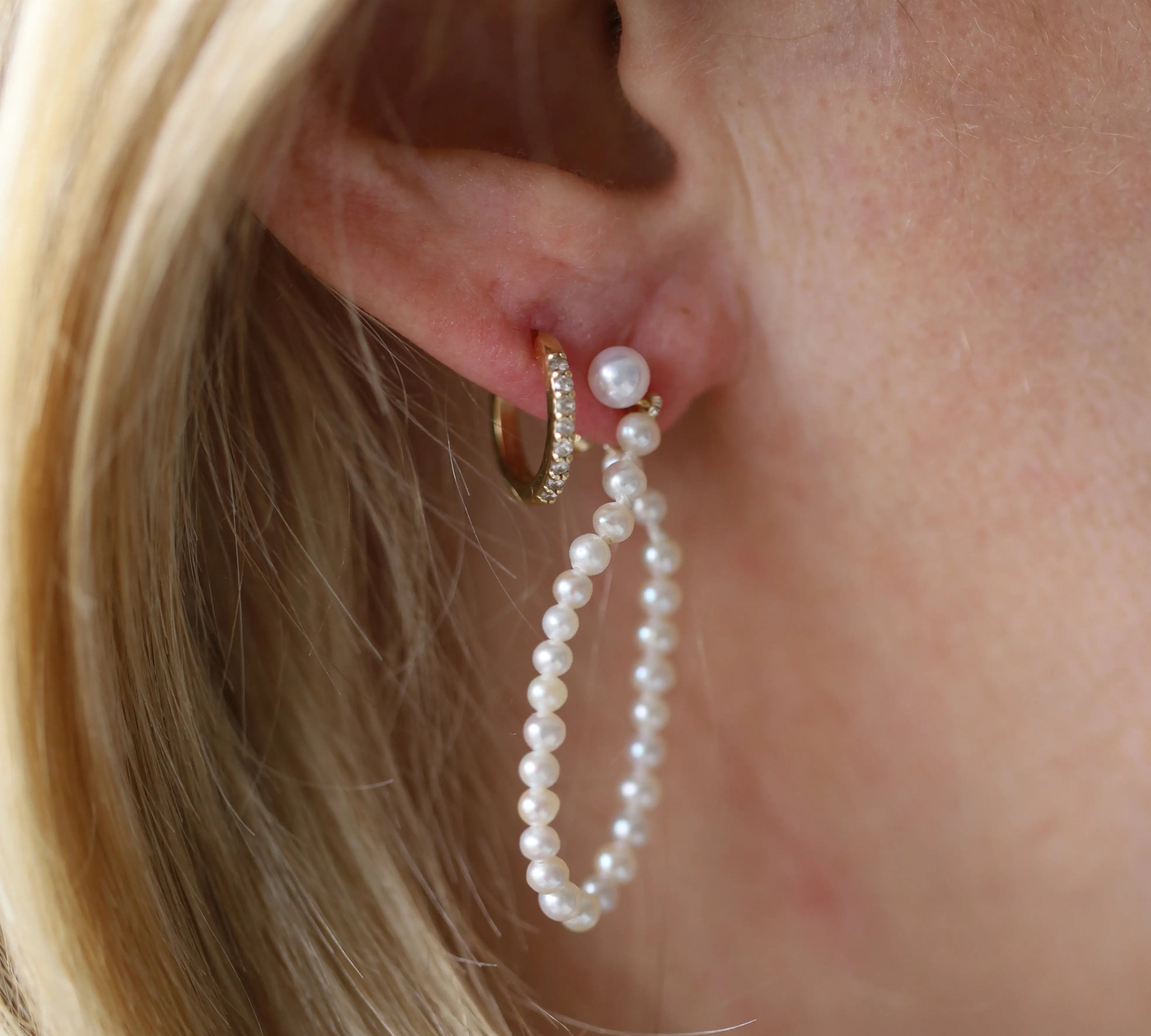 Pearl earring worn by a person with blonde hair.