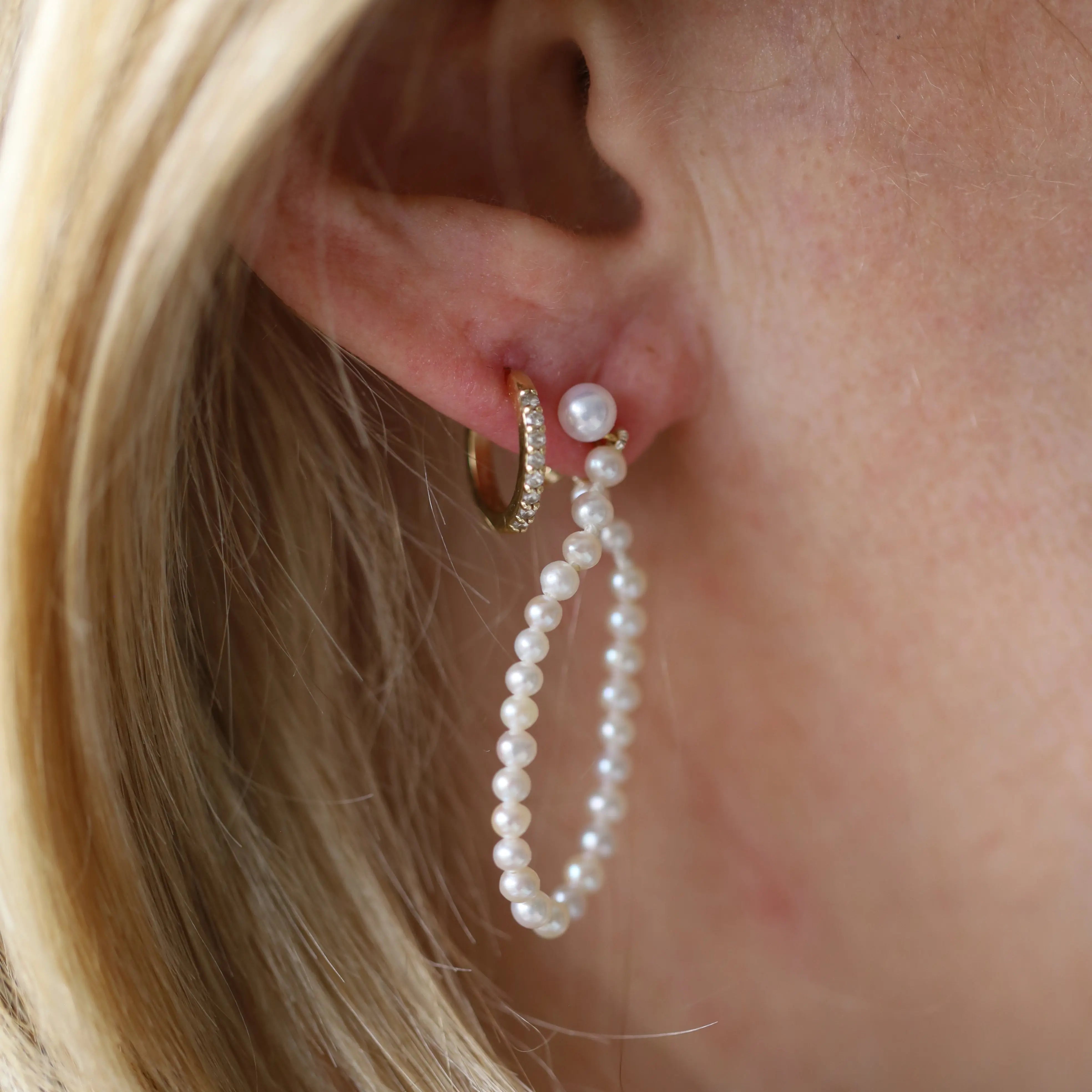 Pearl earring worn by a person with blonde hair.