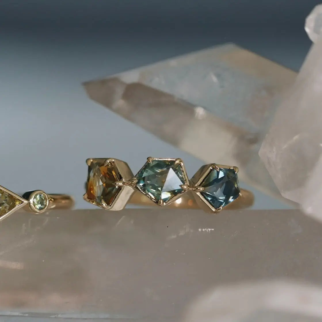 Gold ring with green gemstones on a crystal background