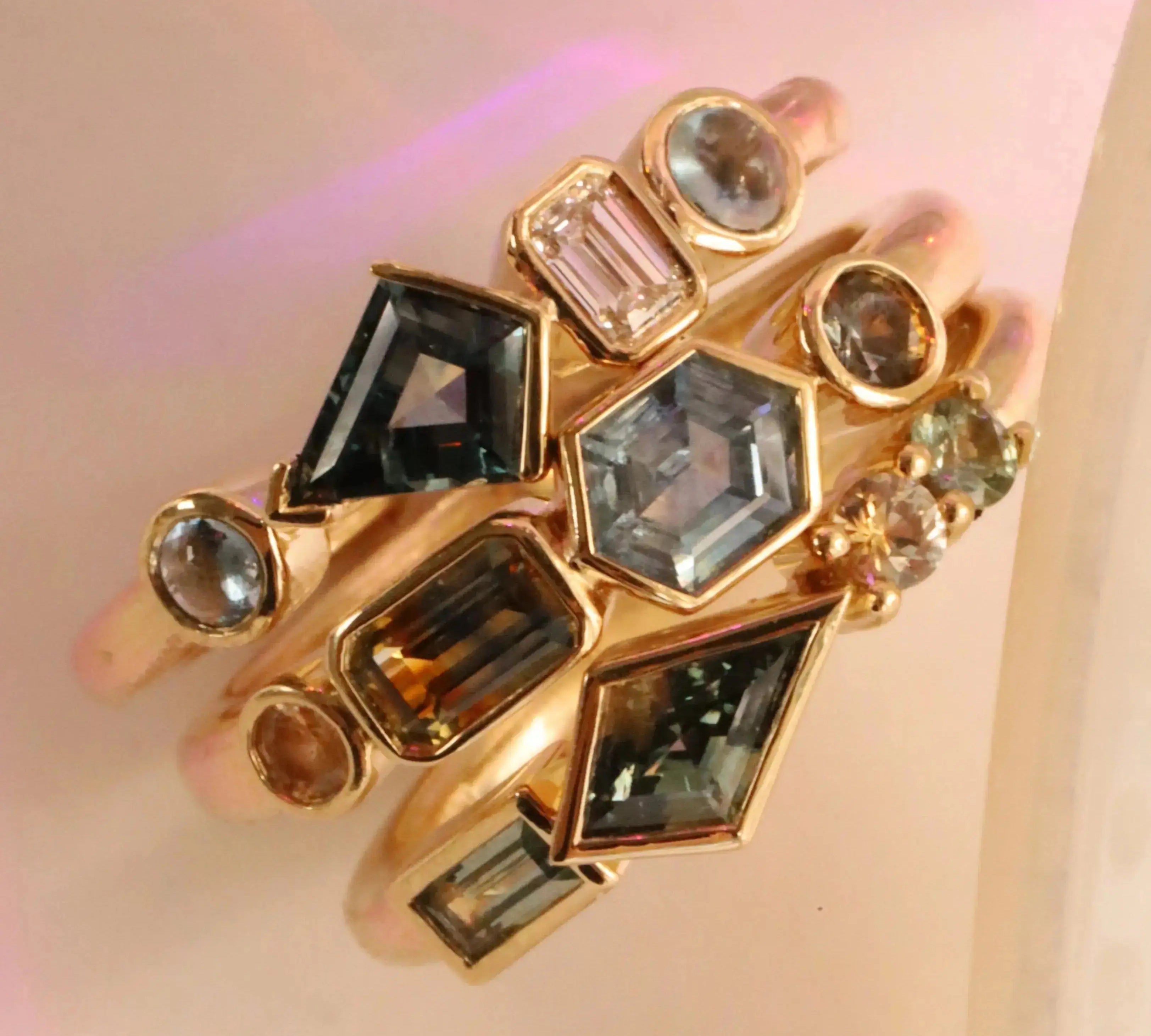 Flat lay of 1.08tcw Montana Sapphire Linear Ring + 0.52ct Montana Sapphire, Sapphire and Diamond Kaleidoscope Ring + 0.62ctw Montana Sapphire Linear Ring