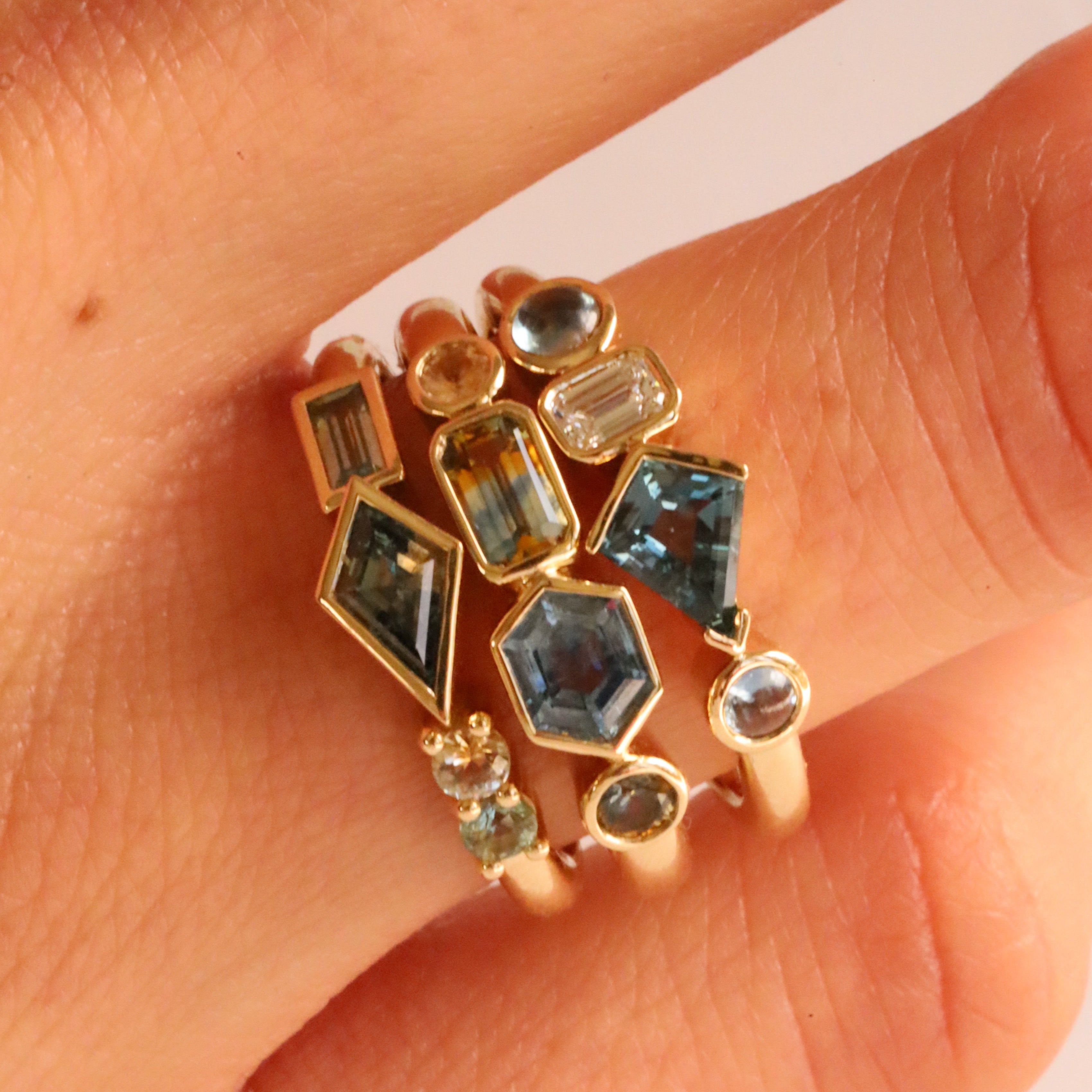 Close up of 1.08tcw Montana Sapphire Linear Ring + 0.52ct Montana Sapphire, Sapphire and Diamond Kaleidoscope Ring + 0.62ctw Montana Sapphire Linear Ring on woman's hand