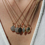 Necklace with five dangling pendant charms on a person wearing a light-colored top.