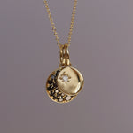 Gold necklace with a round pendant featuring a star design on a gray background