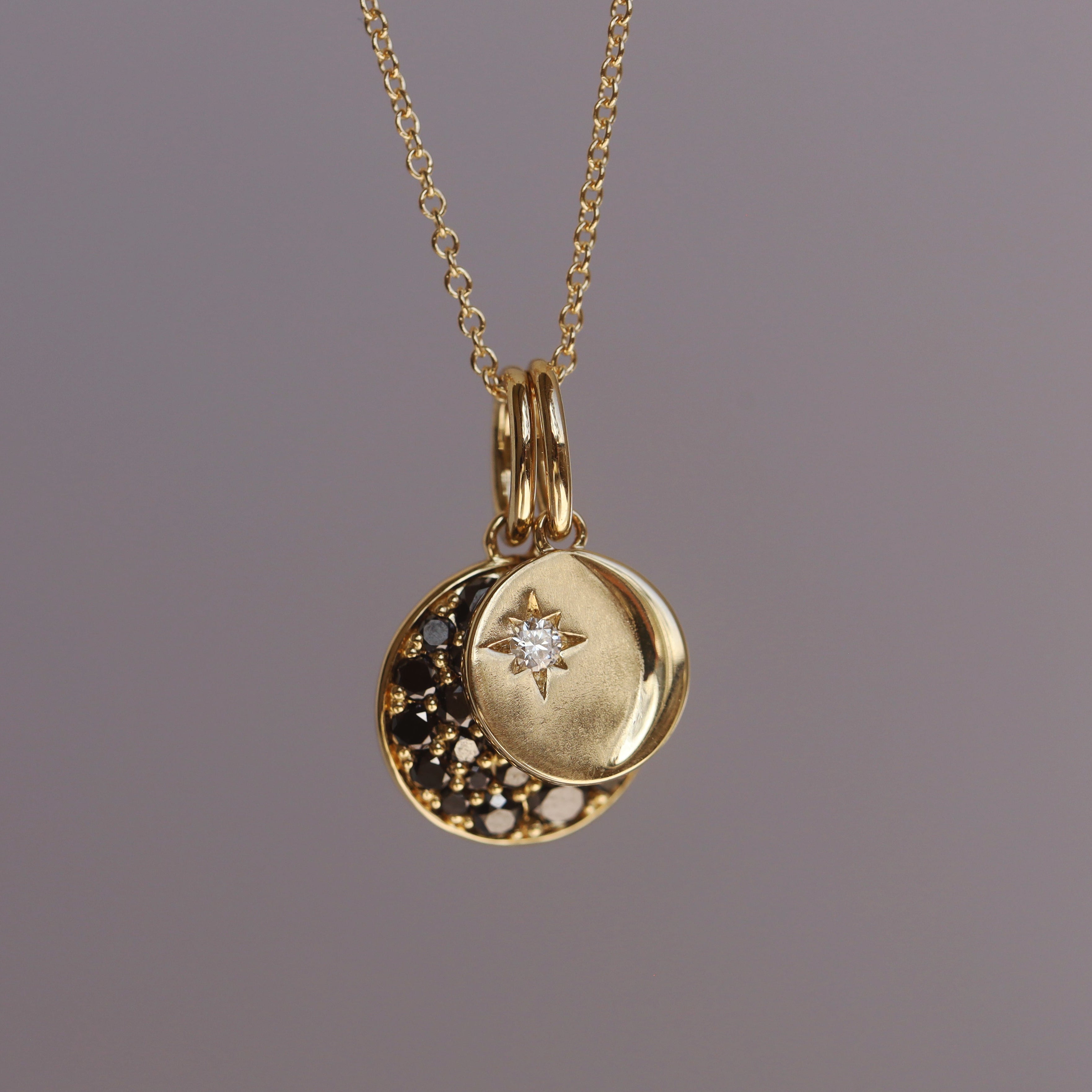 Gold necklace with a round pendant featuring a star design on a gray background