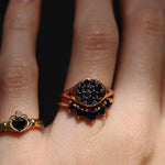 Close-up of a hand wearing two gold rings with gemstones on a dark background